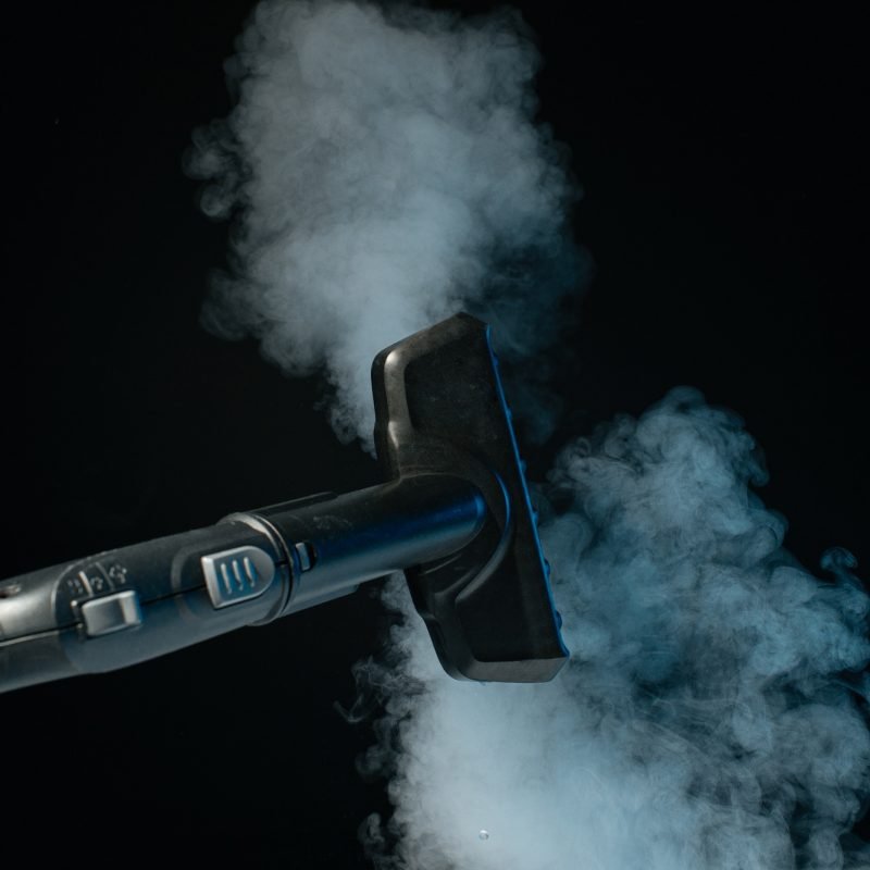 Steam clean brush in hand on black background. Clean concept